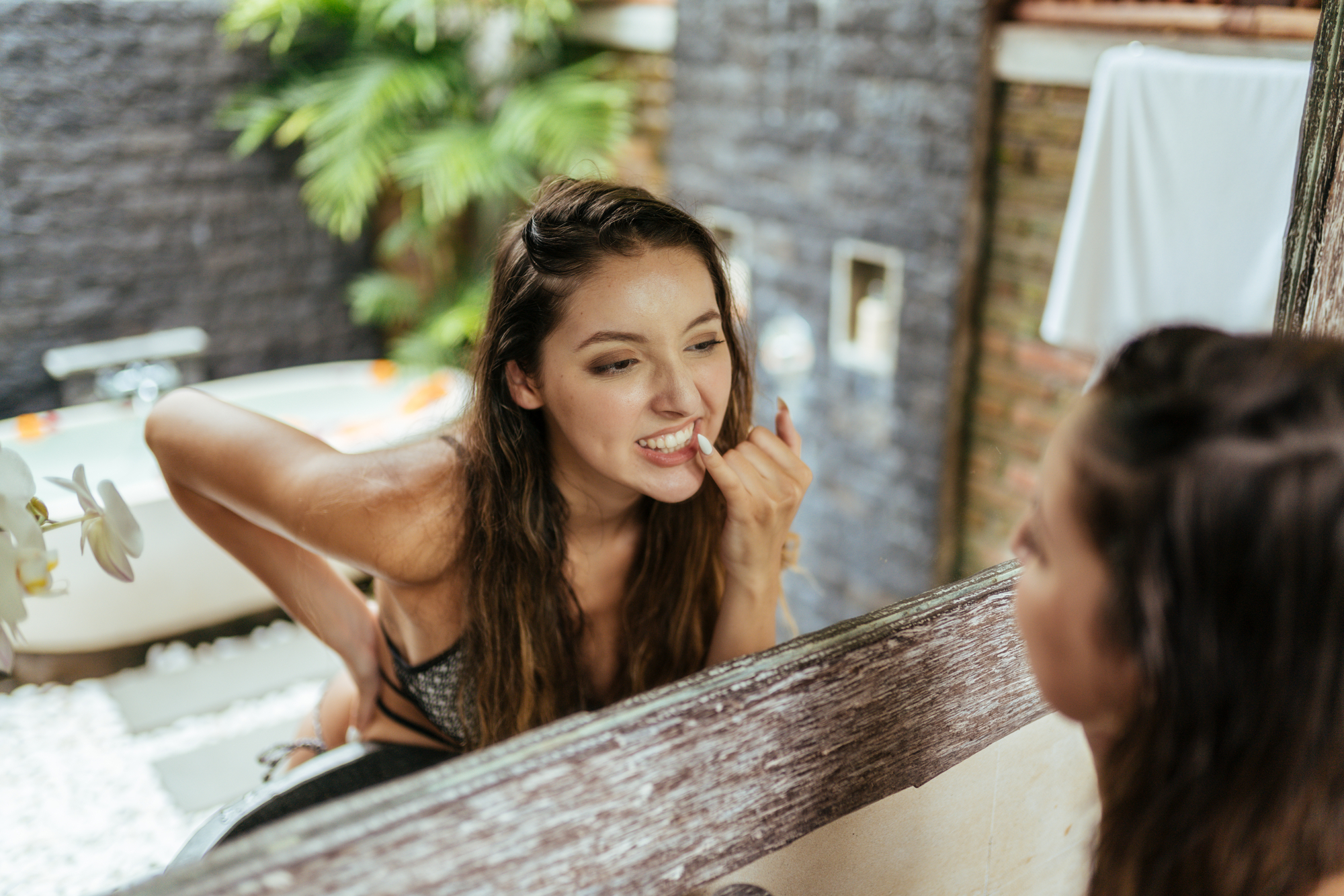 girl in the bathroom in front of the mirror looks at her teeth very carefully